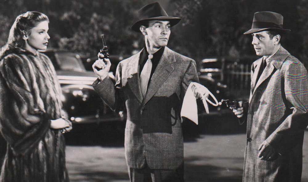 Humphrey Bogart (a destra) è Philip Marlowe in Il grande sonno (1942). A sinistra Lauren Bacall